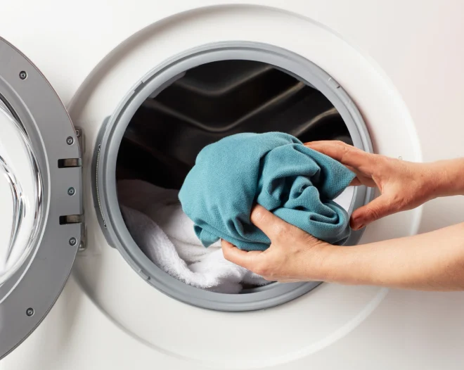 hands putting clothes inside a washing machine